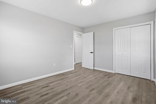 unfurnished bedroom with a closet, baseboards, and wood finished floors