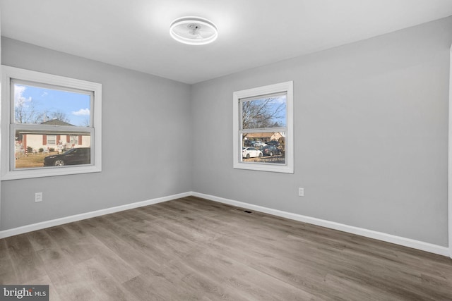 spare room with visible vents, baseboards, and wood finished floors