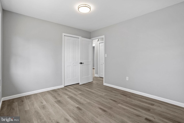 unfurnished bedroom featuring a closet, baseboards, and wood finished floors