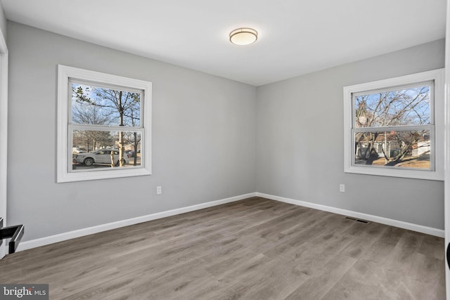 spare room featuring visible vents, baseboards, and wood finished floors
