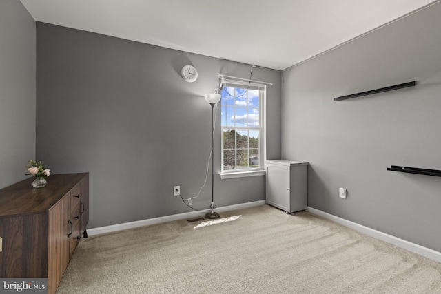 unfurnished room with baseboards and light colored carpet