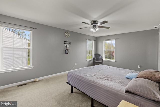 carpeted bedroom featuring baseboards, a ceiling fan, multiple windows, and visible vents