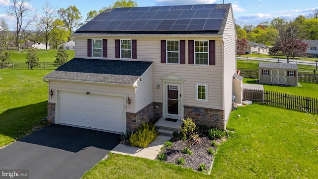 traditional-style home featuring fence, aphalt driveway, a front yard, and solar panels