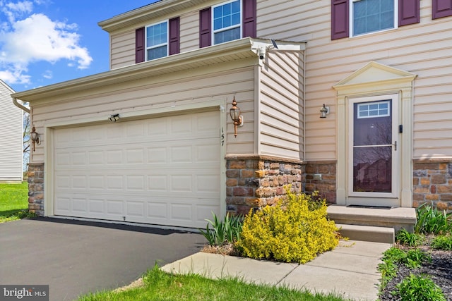 exterior space with an attached garage, driveway, and stone siding