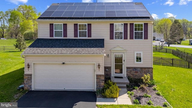 traditional-style home featuring stone siding, driveway, a front yard, and solar panels