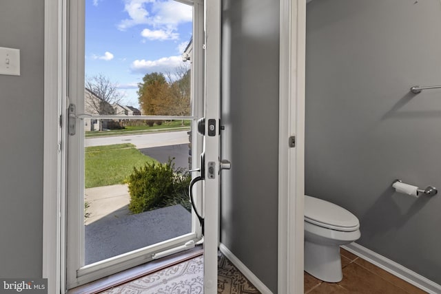 bathroom with toilet, baseboards, and tile patterned floors