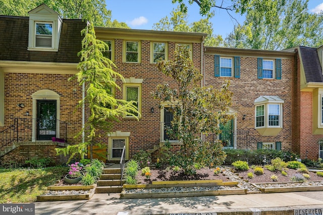 multi unit property featuring roof with shingles and brick siding