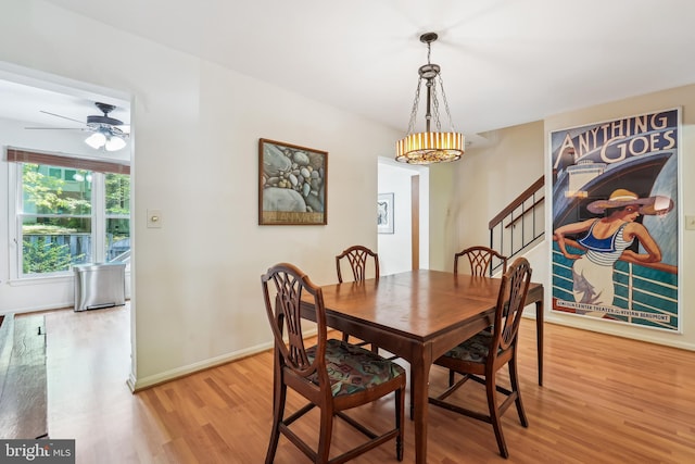 dining space with light wood-style floors, stairway, baseboards, and a ceiling fan