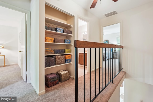 hall with baseboards, an upstairs landing, visible vents, and carpet