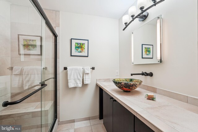 bathroom featuring vanity, baseboards, a shower stall, and tile patterned flooring