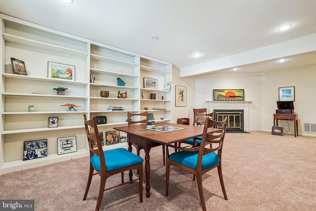 carpeted dining room featuring recessed lighting, visible vents, and a fireplace with flush hearth