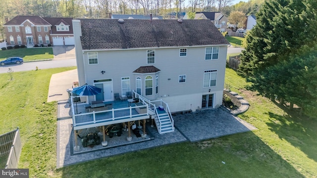 rear view of property with a chimney, a patio, a lawn, and roof with shingles
