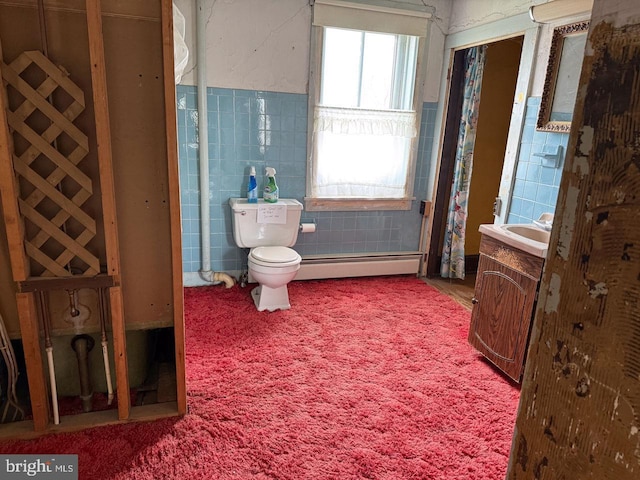 bathroom with toilet, a baseboard heating unit, vanity, and tile walls