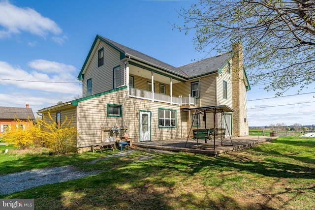 rear view of property featuring a yard, a patio area, and a balcony