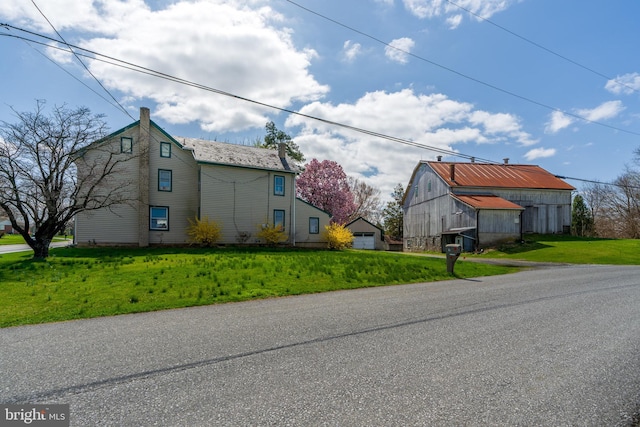 view of property exterior featuring a barn, an outbuilding, and a lawn