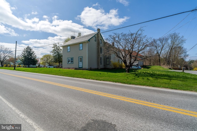 view of home's exterior featuring a chimney and a lawn