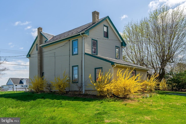 rear view of house with a chimney and a lawn