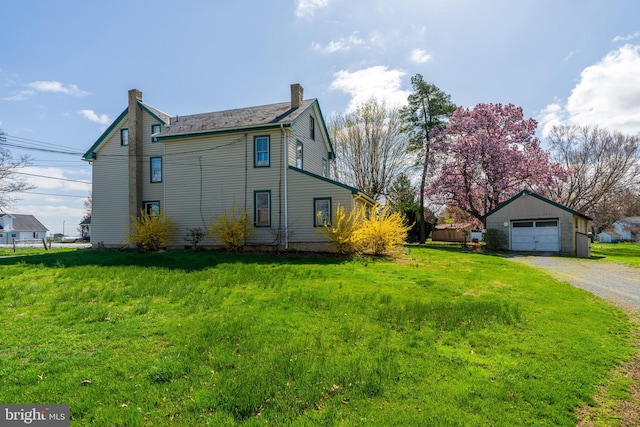 view of home's exterior featuring an outdoor structure, a chimney, a detached garage, driveway, and a yard