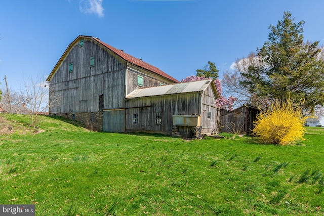back of property with a yard, an outdoor structure, a gambrel roof, and a barn