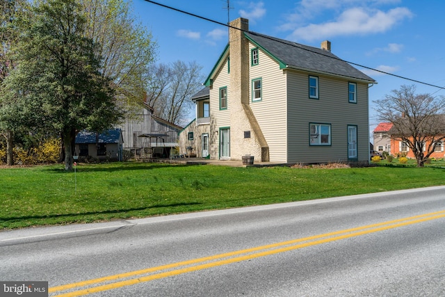 view of side of property featuring a yard and a chimney