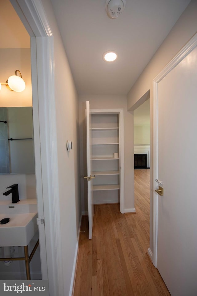 hallway with wood finished floors, a sink, and baseboards