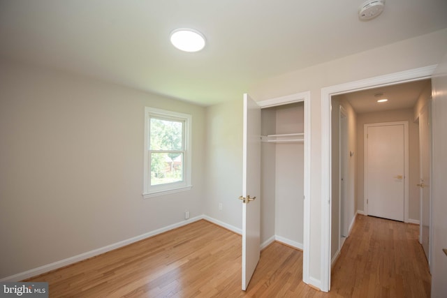 unfurnished bedroom featuring a closet, light wood finished floors, and baseboards