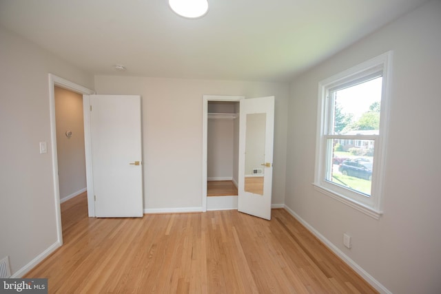 unfurnished bedroom with light wood-style floors, a closet, baseboards, and visible vents