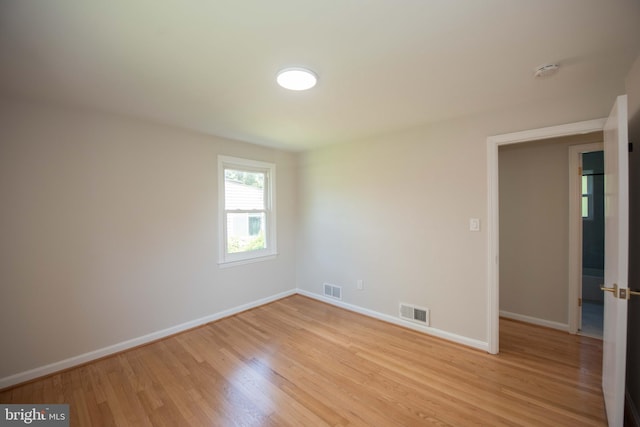 empty room with light wood-style flooring, baseboards, and visible vents