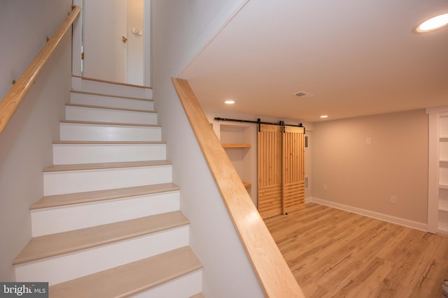 stairs featuring visible vents, recessed lighting, a barn door, wood finished floors, and baseboards