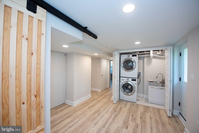 laundry room with baseboards, recessed lighting, light wood-style floors, stacked washer / dryer, and laundry area
