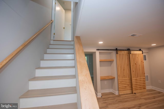 stairs featuring wood finished floors, baseboards, visible vents, and a barn door