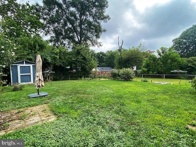 view of yard featuring an outbuilding, fence, and a shed