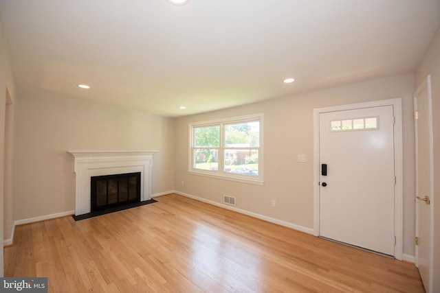 unfurnished living room with visible vents, baseboards, recessed lighting, light wood finished floors, and a fireplace with flush hearth