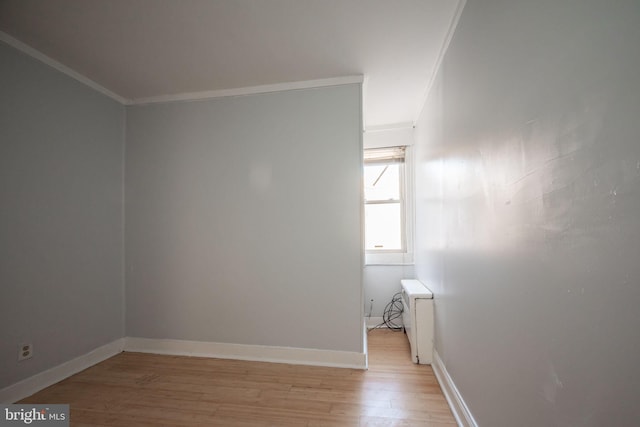 unfurnished room with crown molding, radiator heating unit, light wood-style floors, and baseboards