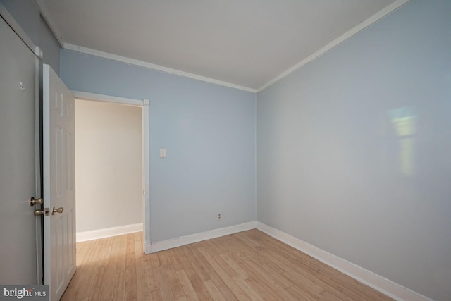 empty room featuring ornamental molding, light wood-style flooring, and baseboards