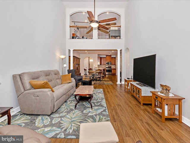6538 Autumn Olive Dr, Frederick, MD 21703 - living area featuring ceiling fan, decorative columns, light wood-style flooring, arched walkways, and baseboards