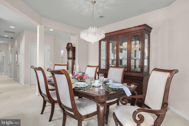 dining area with a chandelier, light colored carpet, baseboards, and visible vents