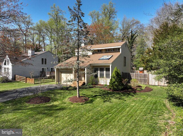 view of front of house featuring a garage, driveway, fence, and a front lawn