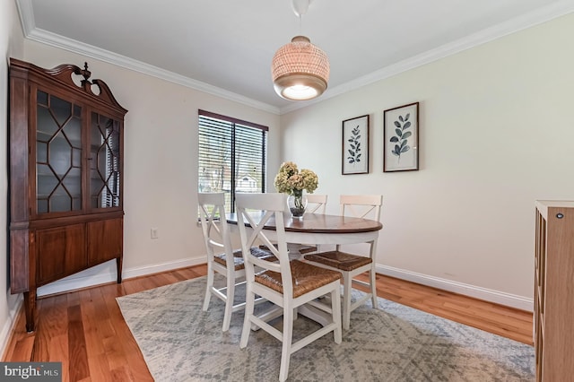 dining space with ornamental molding, baseboards, and wood finished floors