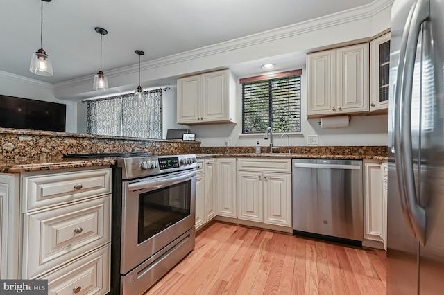 kitchen with dark stone countertops, a sink, crown molding, and appliances with stainless steel finishes