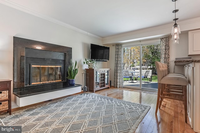 living room featuring ornamental molding, a glass covered fireplace, and hardwood / wood-style flooring
