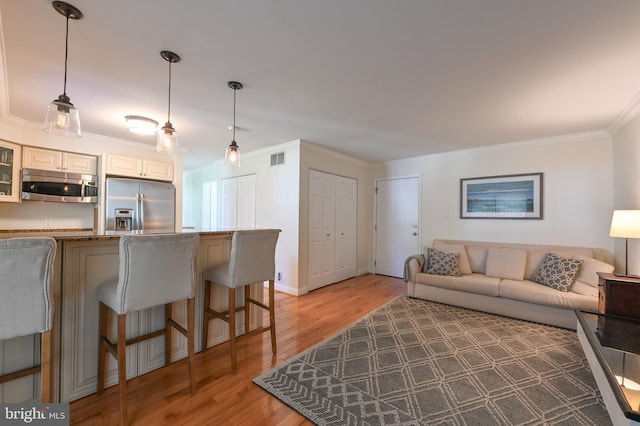living room featuring crown molding, visible vents, and light wood-type flooring