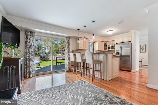 kitchen with glass insert cabinets, light wood-style flooring, crown molding, a breakfast bar area, and stainless steel appliances