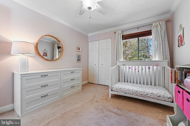 bedroom featuring a closet, baseboards, ceiling fan, crown molding, and light colored carpet