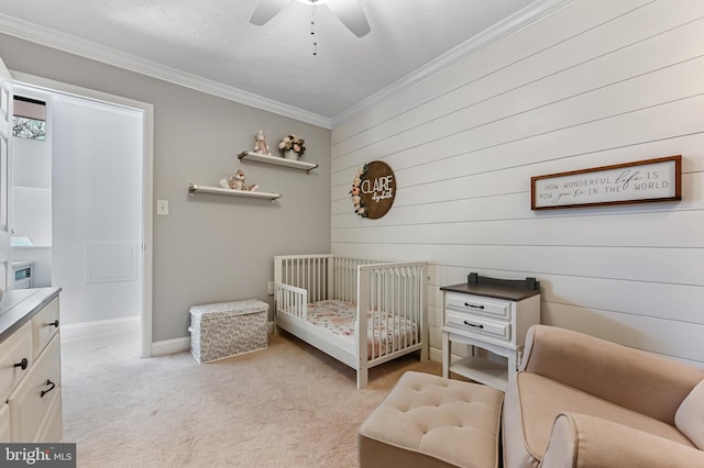 bedroom featuring a nursery area, a ceiling fan, ornamental molding, light carpet, and wooden walls
