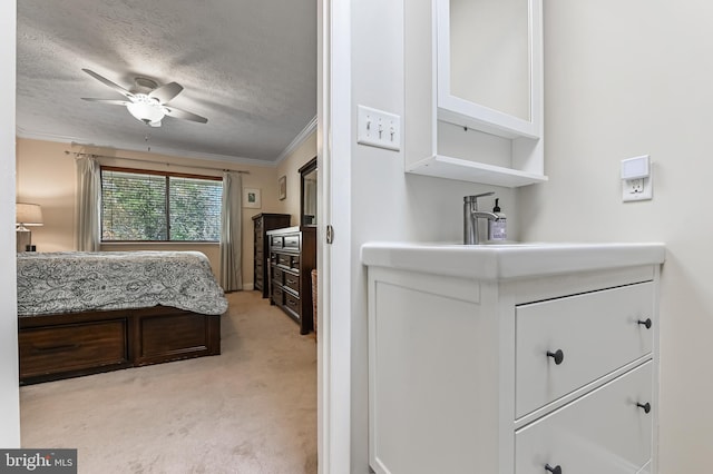 bedroom with ornamental molding, ceiling fan, light colored carpet, and a textured ceiling