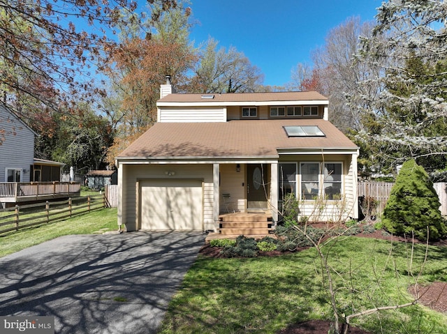 view of front of house featuring a front yard, a garage, a chimney, fence, and driveway