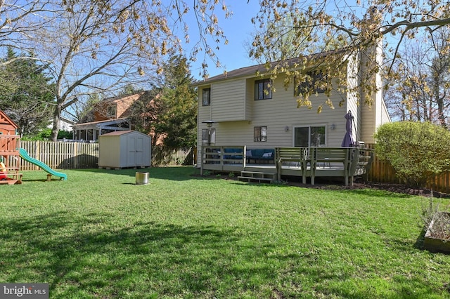 back of property featuring an outdoor structure, a shed, a fenced backyard, a deck, and a playground