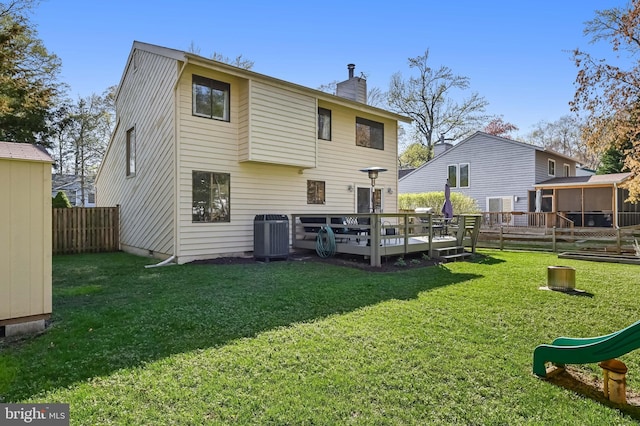 rear view of property featuring central AC, a yard, fence, a chimney, and a deck