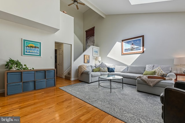 living room featuring a skylight, wood finished floors, a ceiling fan, and stairway
